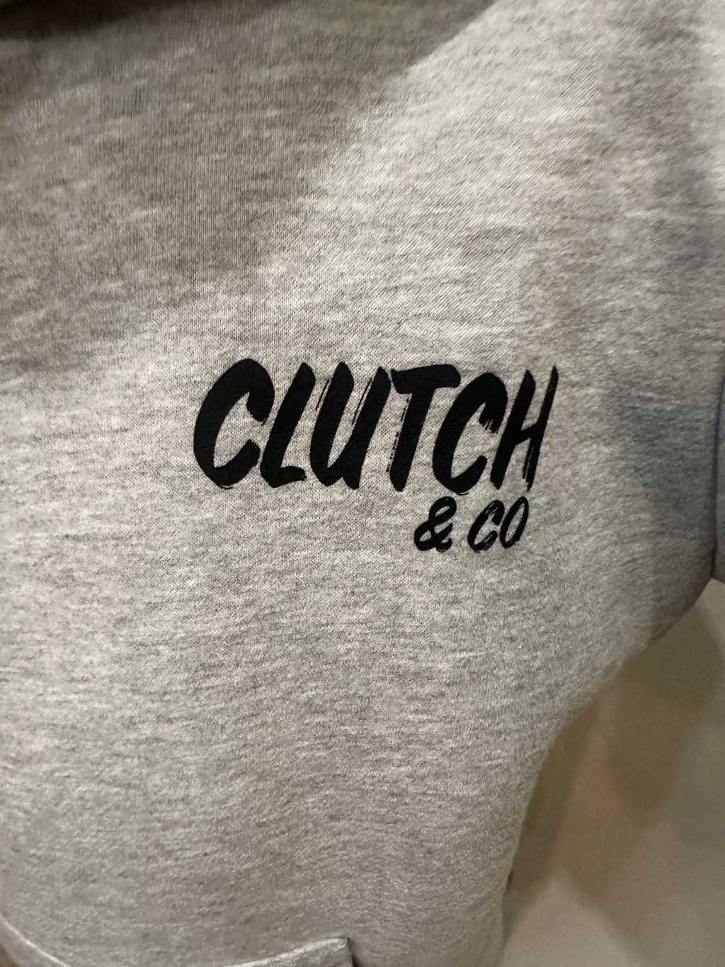 Gray sweatshirt with 'Clutch & Co' text on a plain background