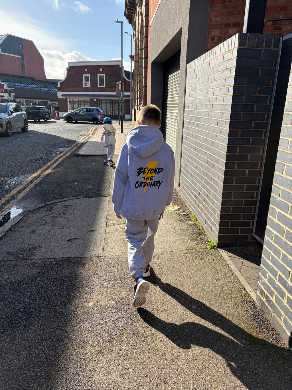 Person walking on a street with buildings and cars in the background