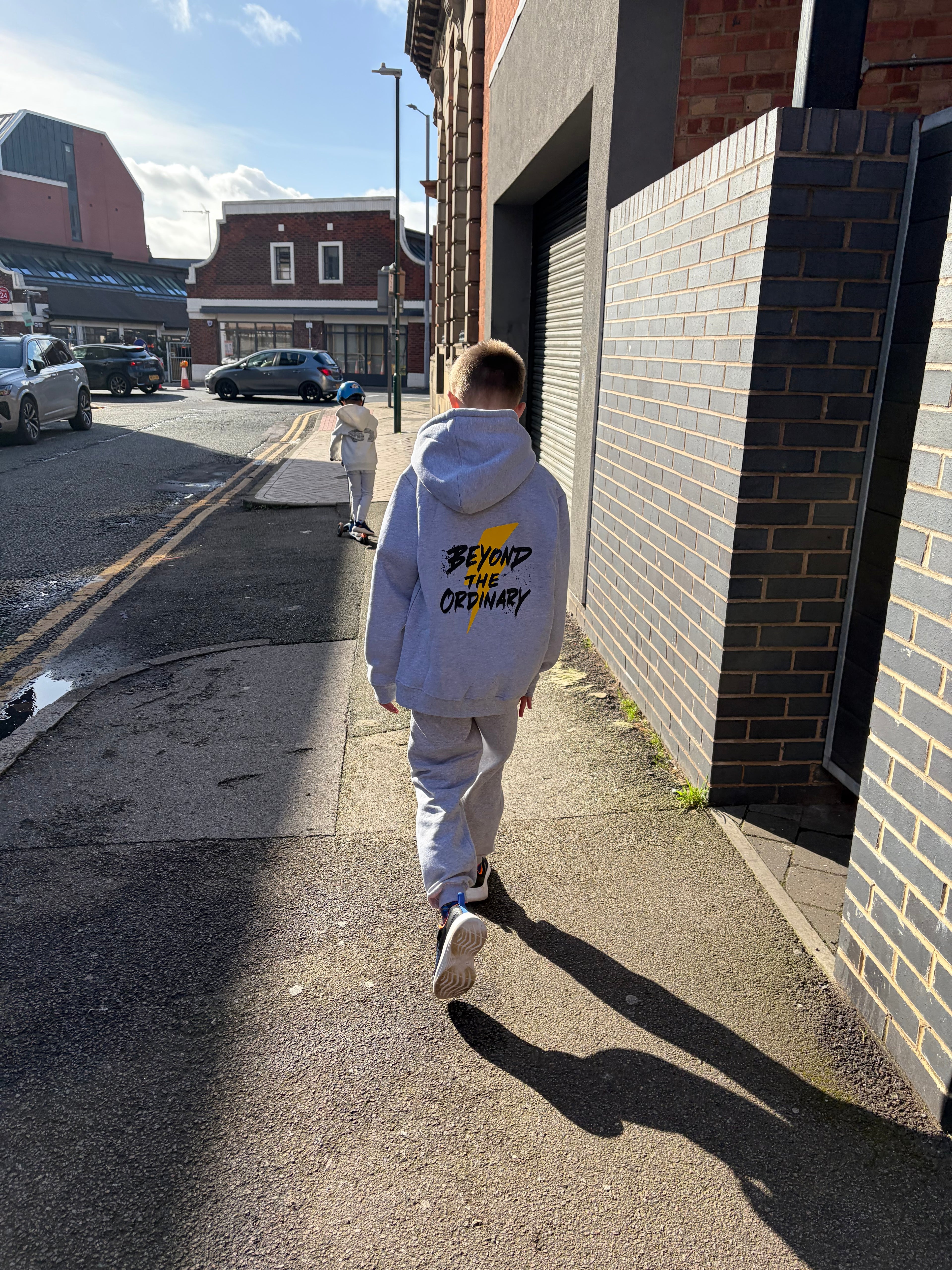 Person walking on a street with buildings and cars in the background