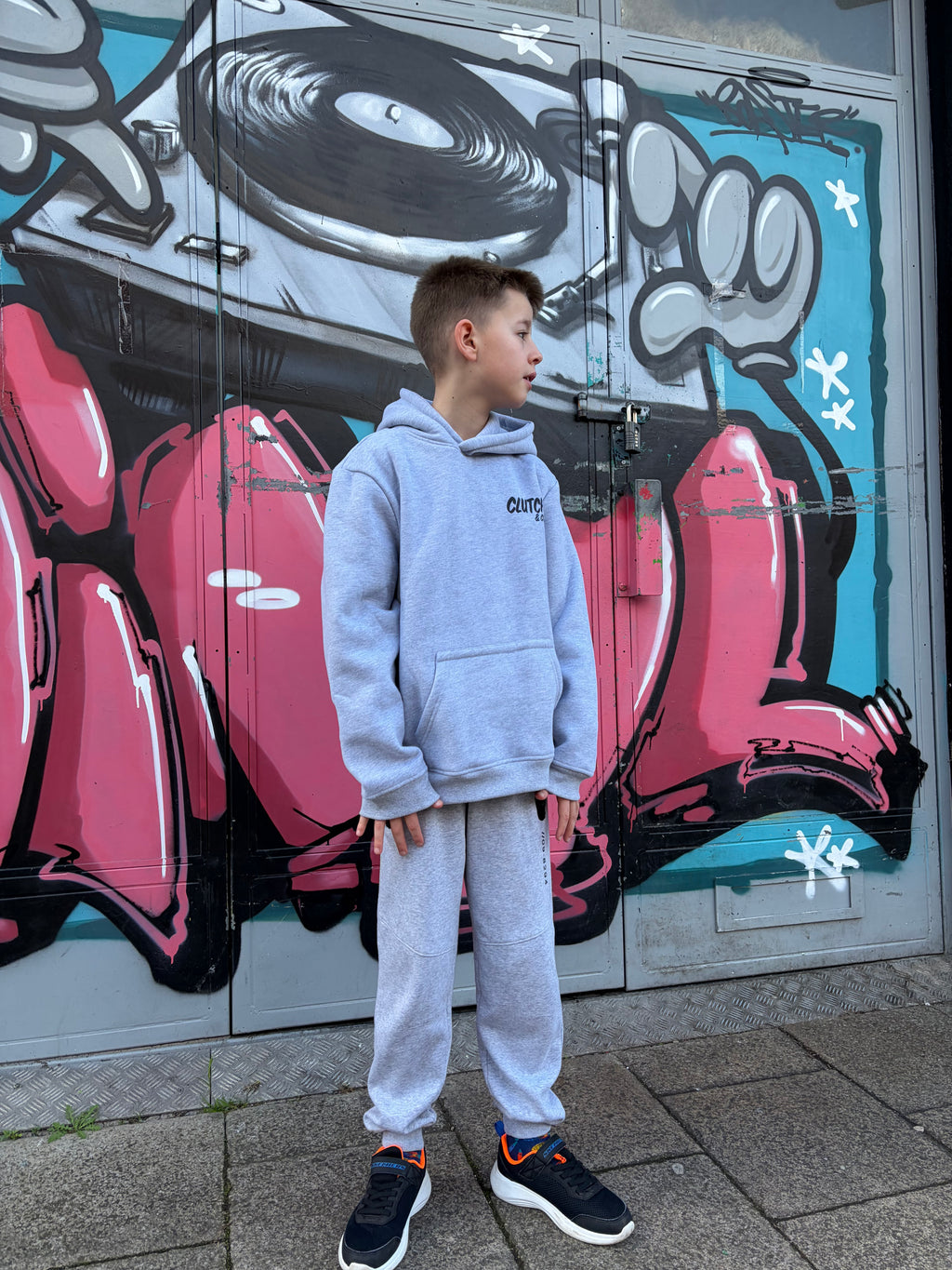 Person standing in front of a colorful mural on a wall.