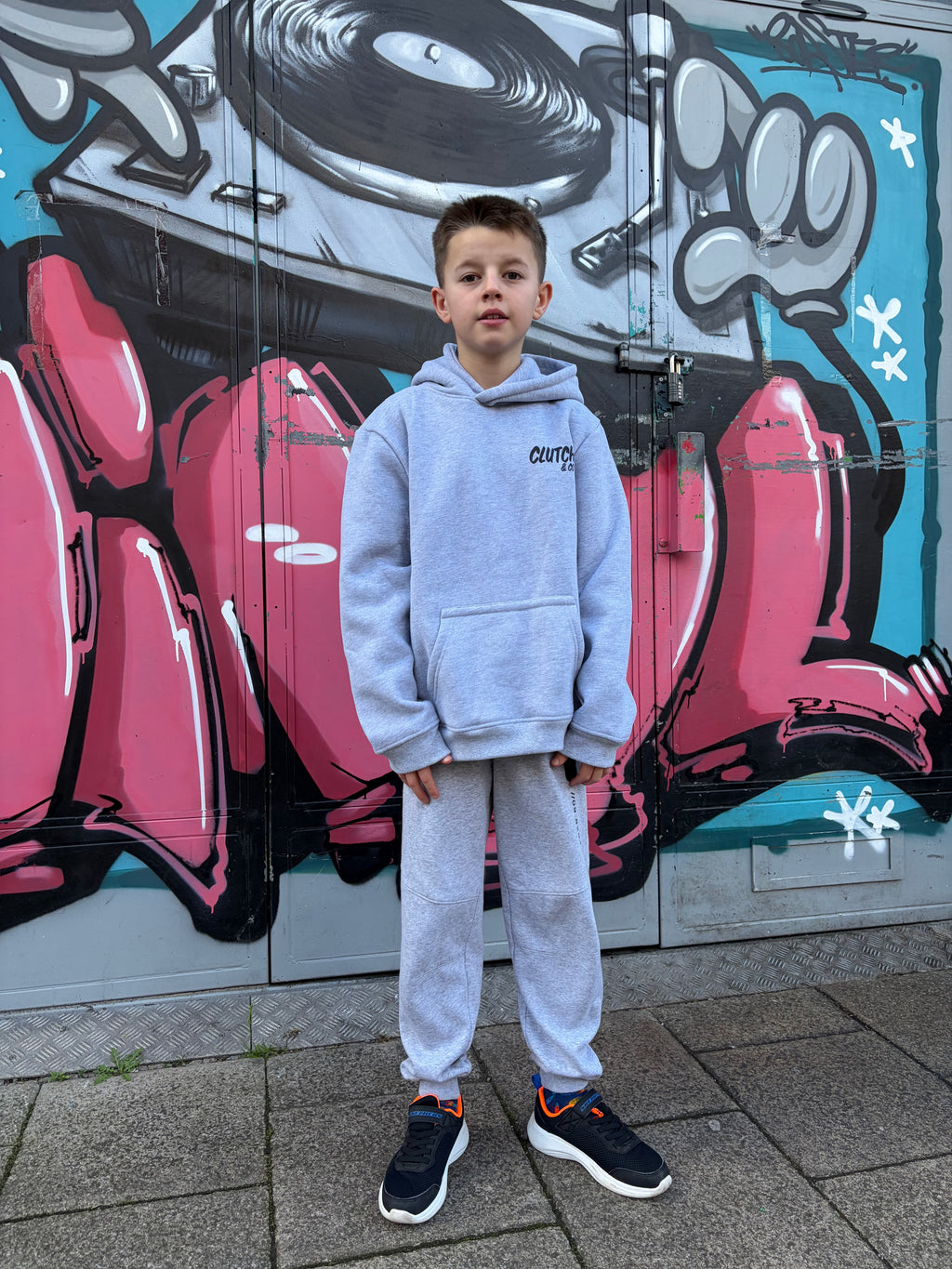 Person standing in front of a colorful mural on a wall.