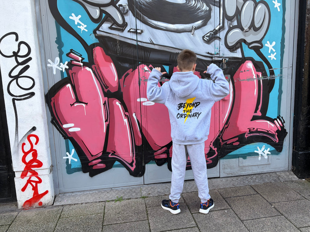 Person standing in front of a colorful graffiti mural on a wall.