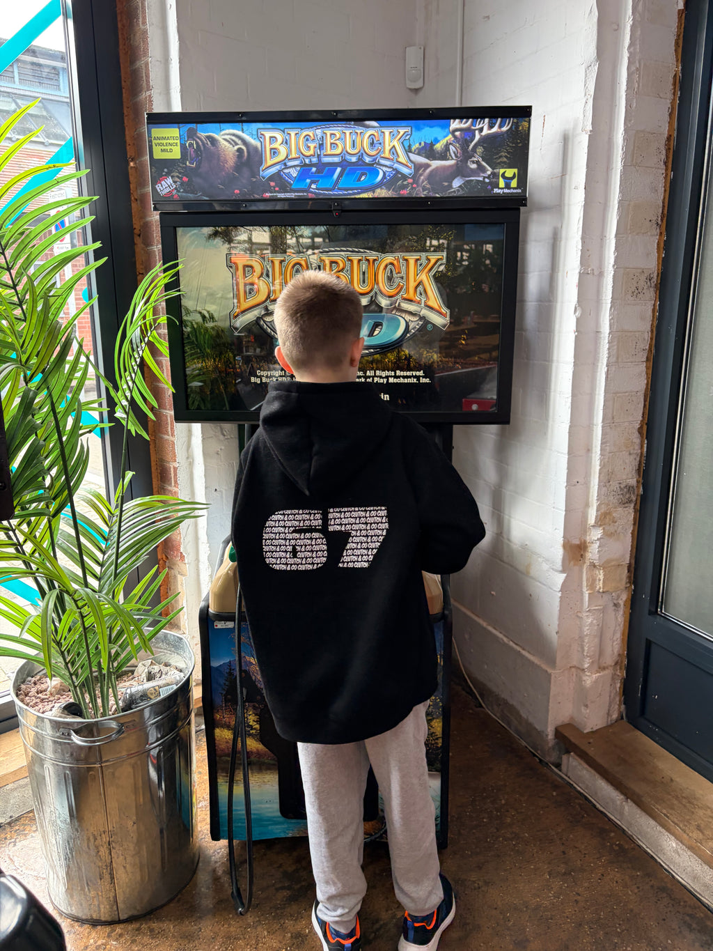 Person wearing a black hoodie with '67' design standing in front of a movie poster for 'Big Buck'.