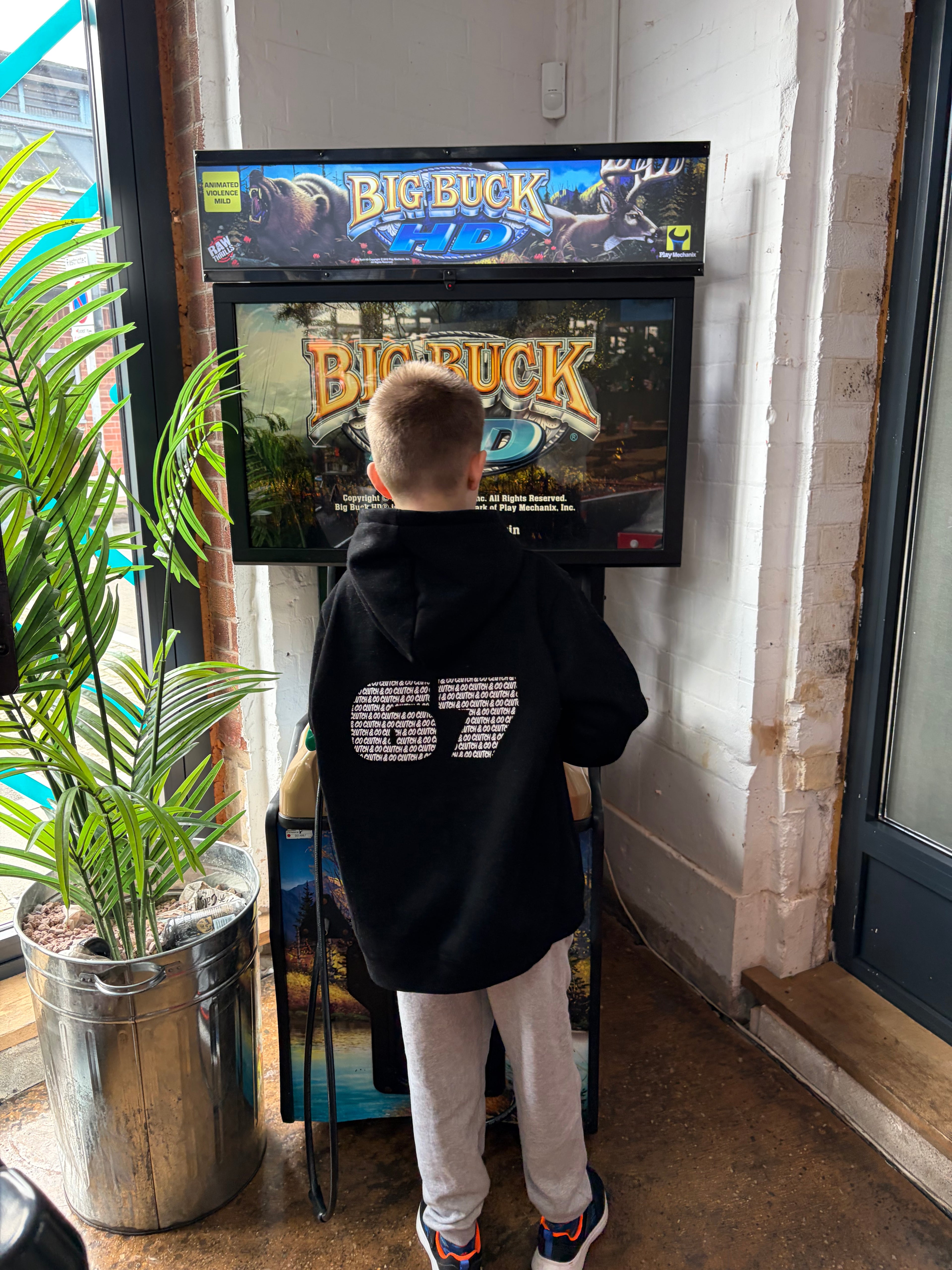 Person wearing a black hoodie with '67' design standing in front of a movie poster for 'Big Buck'.